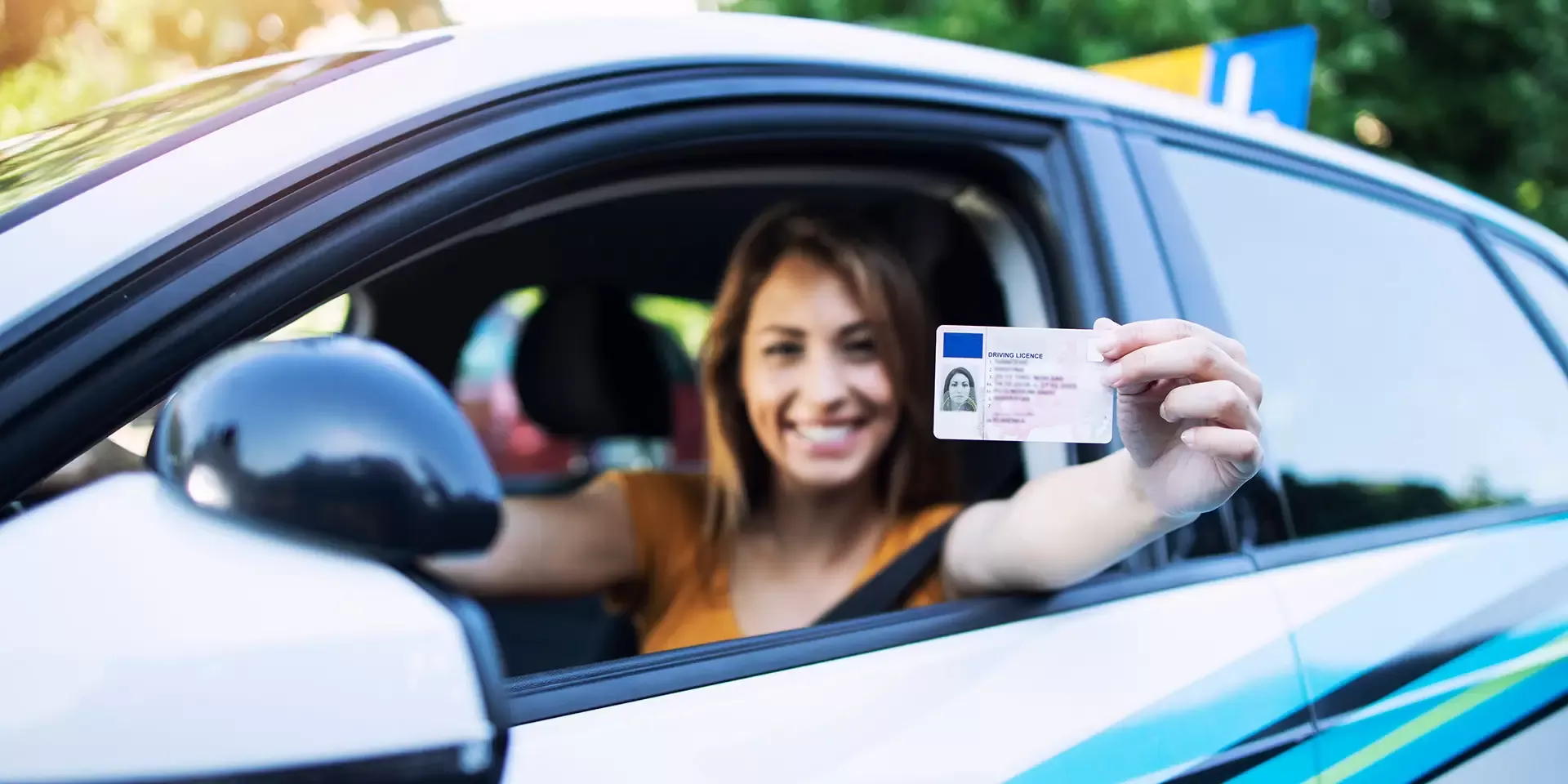 Meisje in auto met rijbewijs in hand